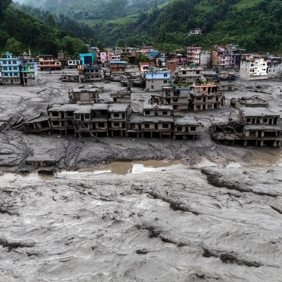 Damaged buildings and houses covered in mud next to the Likhu River following deadly flash floods and mudslides in Devighat, Nepal.