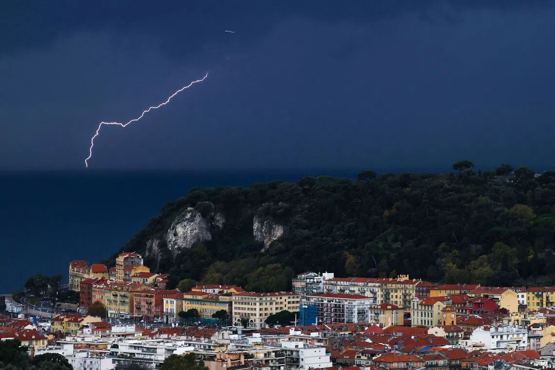 An airplane taking off as lightning illuminates the horizon in the city of Nice, in southern France, on Dec 1, 2025. 