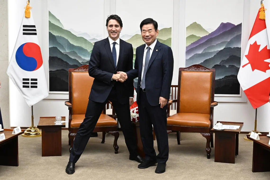 Canadian PM Justin Trudeau (left) bent down momentarily to South Korean National Assembly speaker Kim Jin-pyo's height.