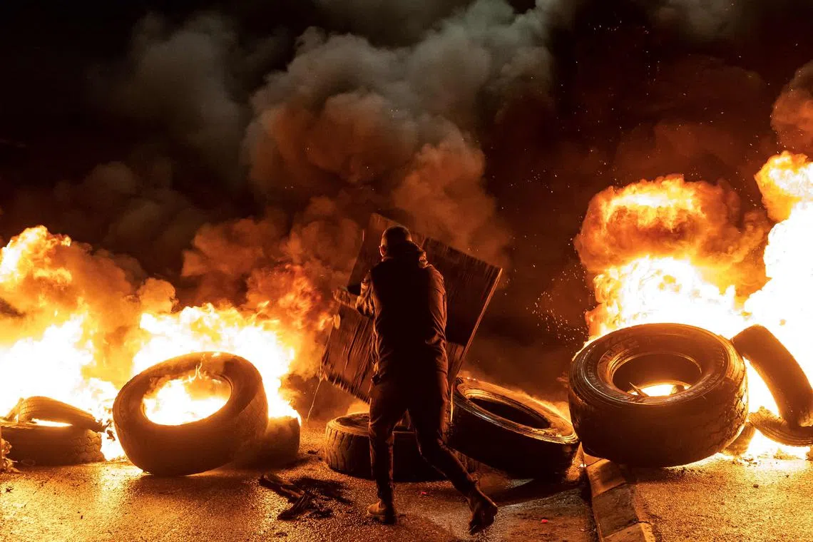 A protester walks near burning tyres in the occupied West Bank on Nov 27, ahead of an expected release of Palestinian prisoners in exchange for Israeli hostages held by Hamas. Israel's prison authority said that 33 Palestinian prisoners had been released "during the night" under the terms of a truce deal that returned hostages from the Gaza Strip. 
