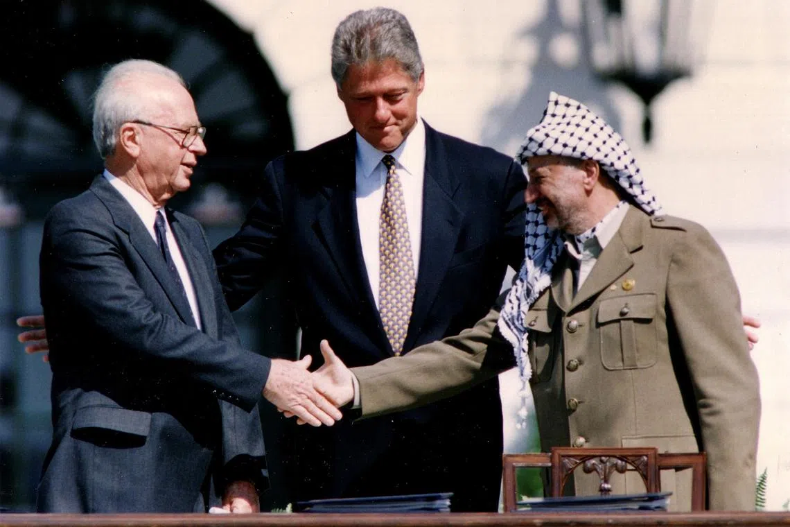 In September 1993, then-Israeli PM Yitzhak Rabin (left) shakes hands with Palestine Liberation Organization Chairman Yasser Arafat, as US President Bill Clinton witnesses the signing of the Israeli-PLO peace accord, at the White House.