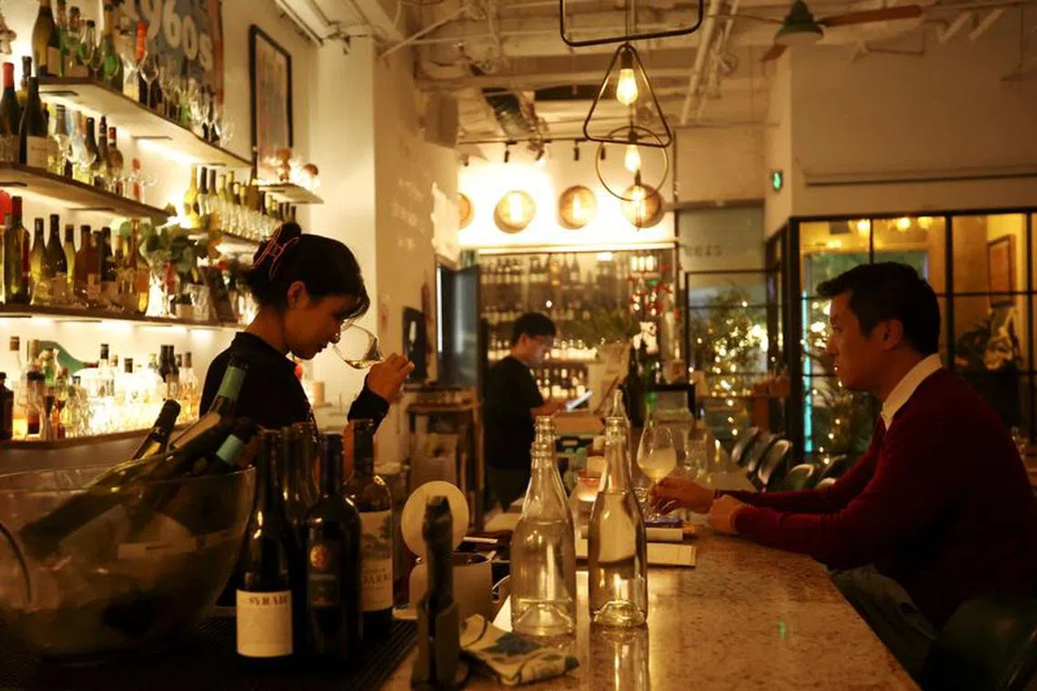 FILE PHOTO: A staff member sniffs wine in a glass while a customer watches at  theTrio Wine Bar in Beijing, China November 1, 2023. REUTERS/Florence Lo/File Photo
