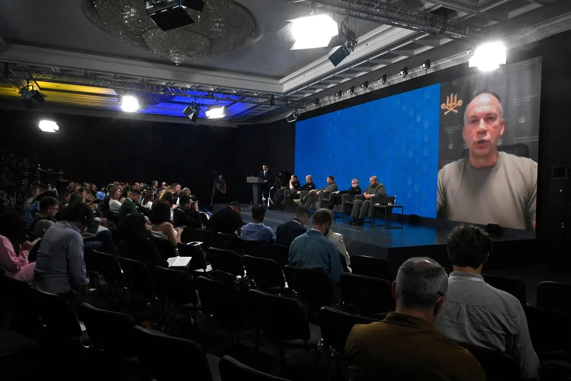 Commander-in-Chief of Armed Forces of Ukraine Oleksandr Syrskyi (displayed on screen -R) speaks via a video call during a joint press conference in Kyiv, on August 27, 2024, amid the Russian invasion of Ukraine. (Photo by Sergei CHUZAVKOV / AFP)