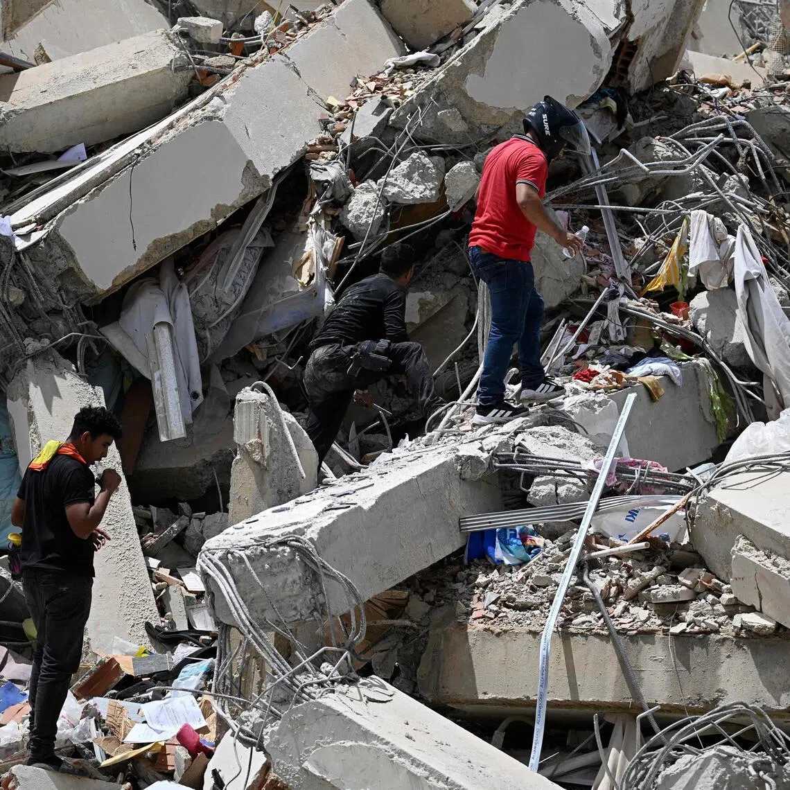 Volunteers search for possible victims in a collapsed building following twin earthquakes in Caraballeda, Caracas, on June 25.