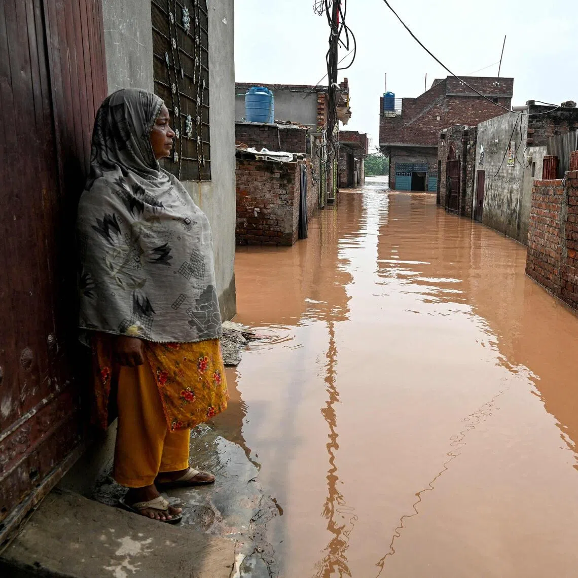 Ghulam Bano stands near her submerged home, after floodwaters entered from the overflowing Ravi river in Shahdara, Lahore on August 29, 2025. PHOTO: AFP