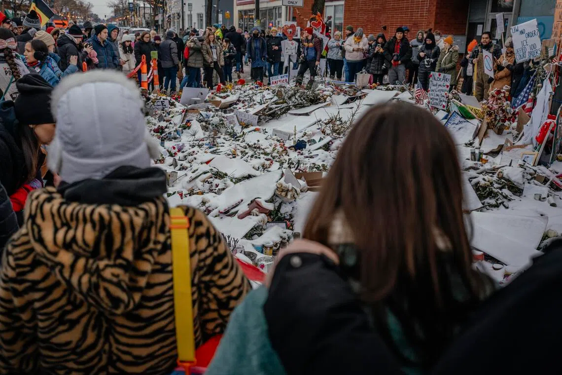 People gather near a makeshift memorial for Mr Alex Pretti at the site where he was fatally shot by federal immigration agents in Minneapolis.