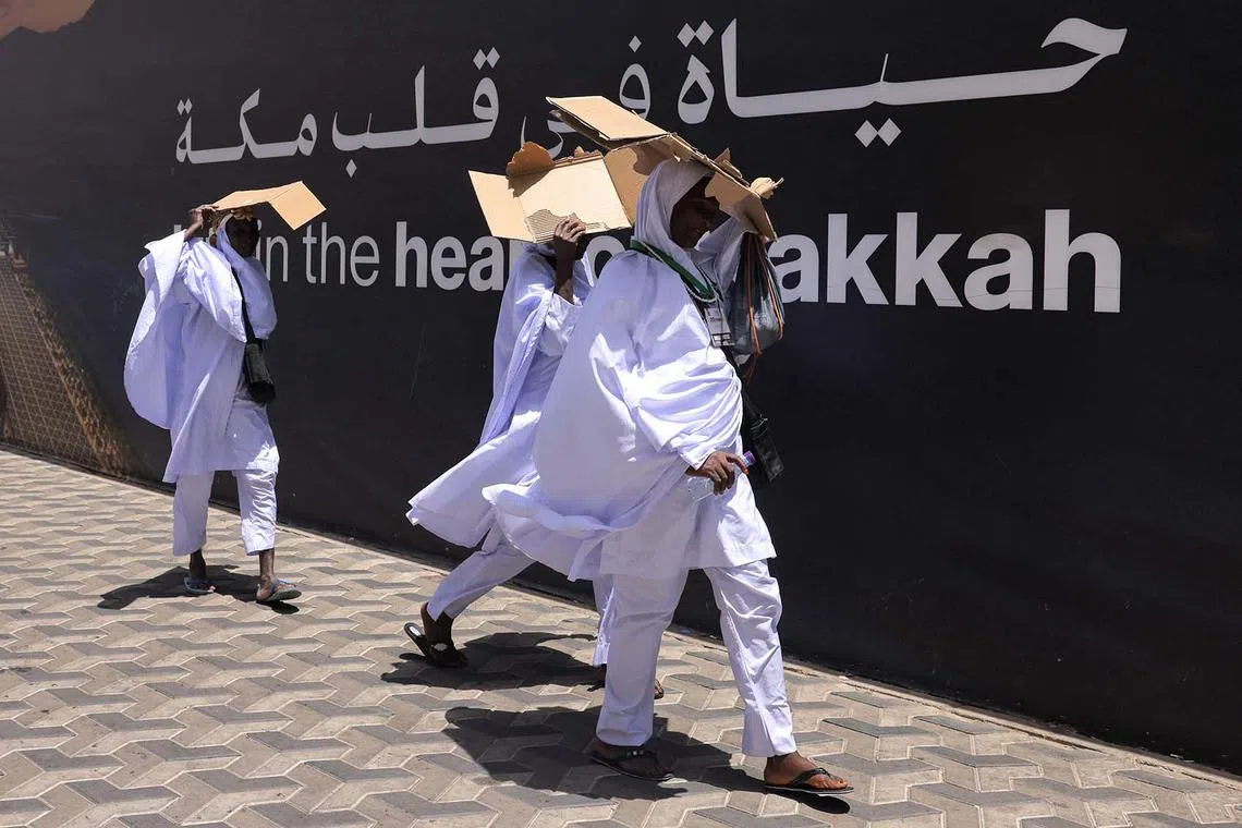 Muslim worshippers using carboard to shield from the sun as they walk on the streets in Saudi Arabia's holy city of Mecca during the annual Hajj pilgrimage on June 2, 2025. The annual hajj pilgrimage, one of the five pillars of Islam, will start on June 4 with well over one million Muslims from around the world expected to take part. 