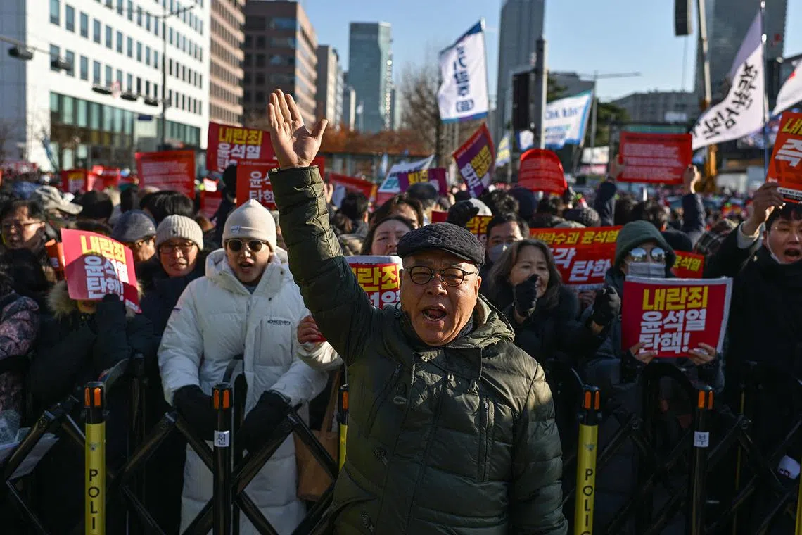Shin Jae-hyung (C), a 66-year-old protester who participated in South Korea's pro-democracy mass protests in the 1970s and the 80s, takes part in a protest calling for the ouster of South Korea President Yoon Suk Yeol outside the National Assembly in Seoul on December 7, 2024. In 1973, when Shin Jae-hyung was a teenager, he was out in the streets being teargassed, fighting against South Korea's then-military dictator Park Chung-hee. He never thought he would have to do it again in 2024. But when he heard the country's current president, Yoon Suk Yeol, had declared martial law this week -- the first time democratic South Korea had experienced it in 40 years -- he raced to the National Assembly thinking: "We must stop this." (Photo by ANTHONY WALLACE / AFP) / To go with AFP story SKorea-politics-unrest-democracy-history, REPORTAGE by Kang Jin-kyu
