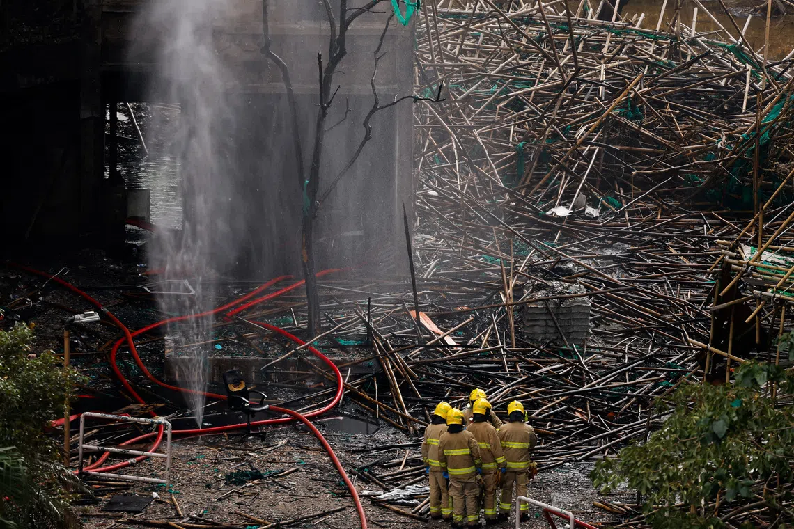 Firefighters gather next to bamboo scaffolding debris at the Wang Fuk Court housing complex after the deadly fire, in Tai Po, Hong Kong, China, December 1, 2025. REUTERS/Maxim Shemetov