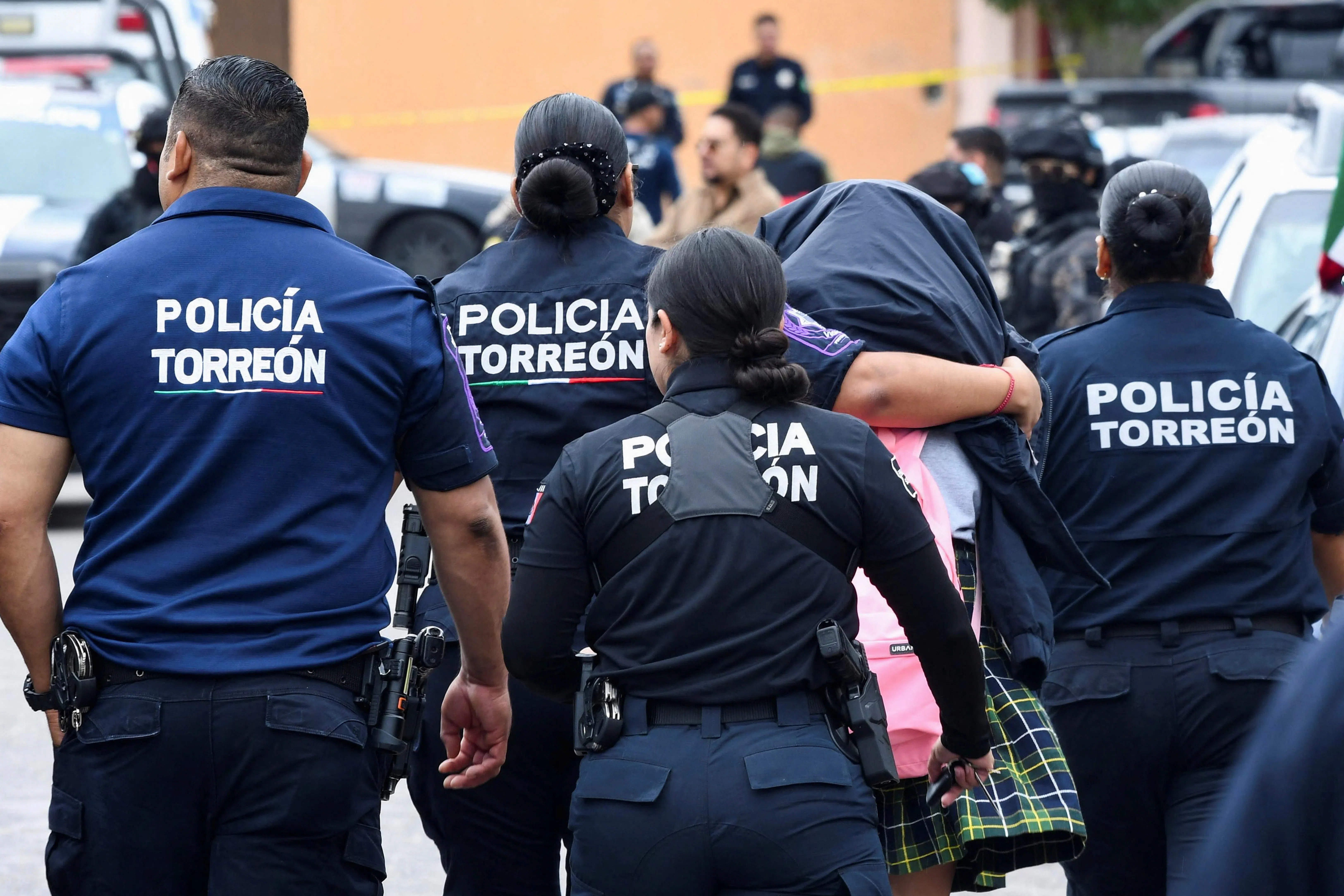 Police officers escorting a student from Secondary School No. 13 to safety.