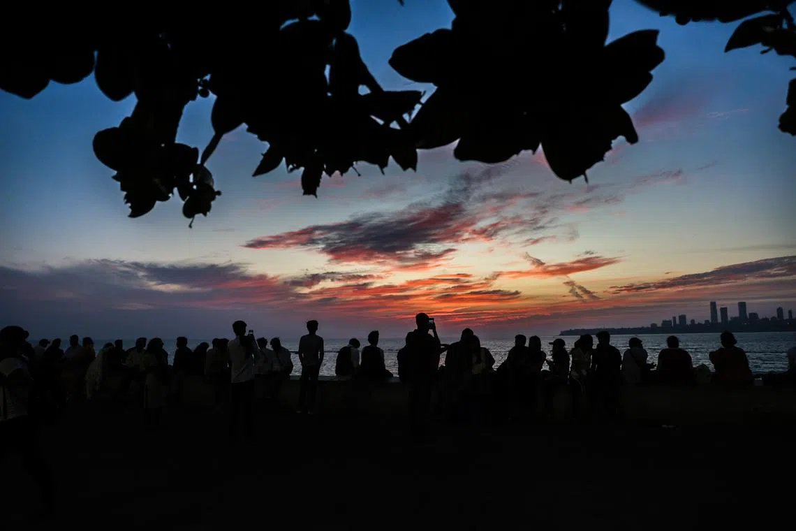 People enjoying the sunset along the Marine Drive promenade, one of the famous sunset spots near the Arabian Sea shore in Mumbai, India, on Mar 17, 2025.  