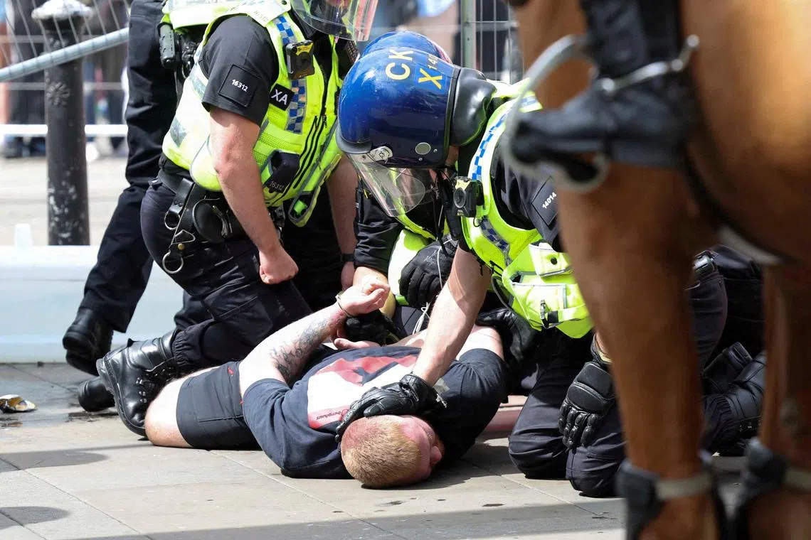 Police officers detain an anti-immigration demonstrator during a protest in Manchester, Britain, August 3, 2024. REUTERS/Manon Cruz