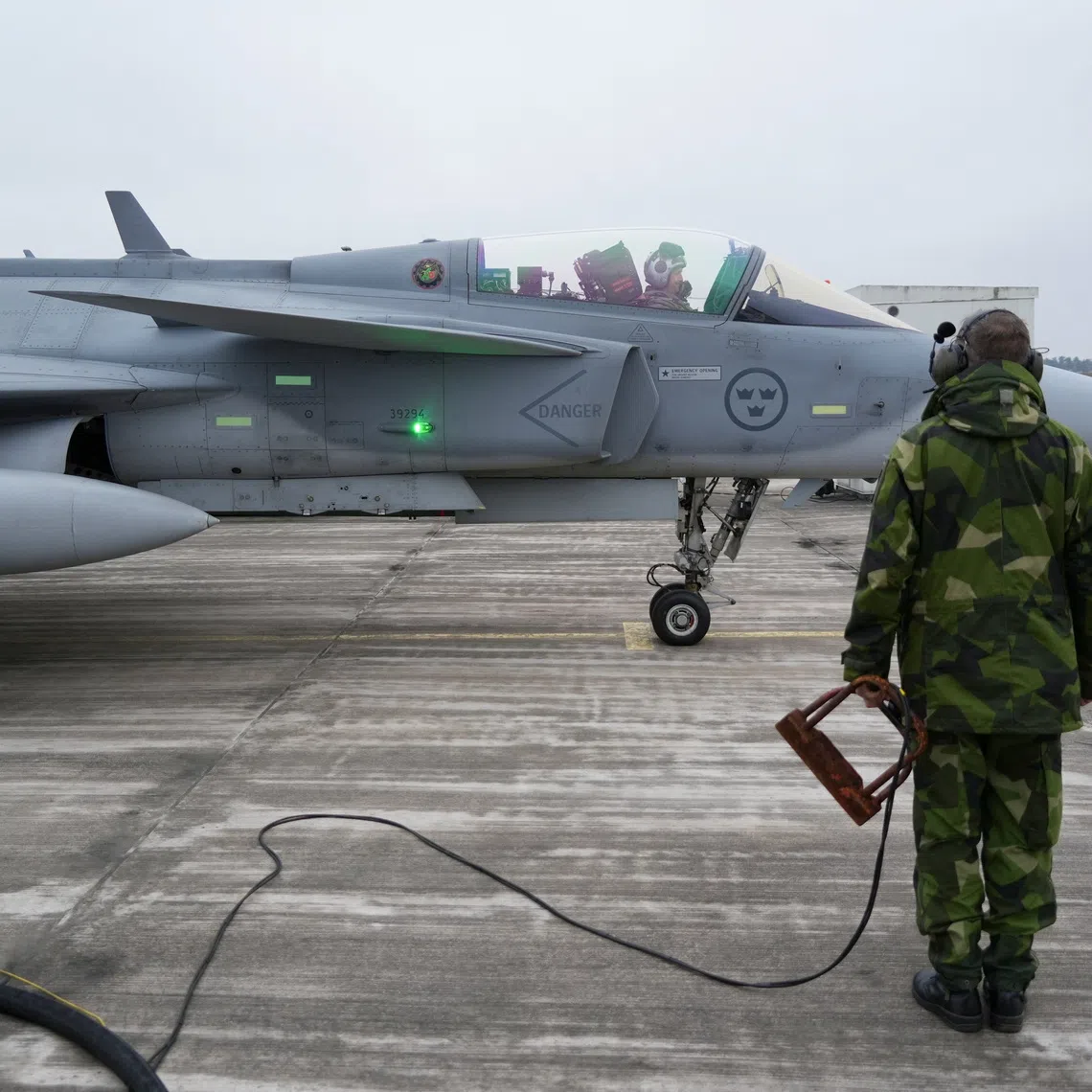 A member of the ground crew of the Swedish Air Force stands next to a JAS 39 Gripen fighter aircraft in Kallinge, Sweden, December 16, 2025. REUTERS/Tom Little