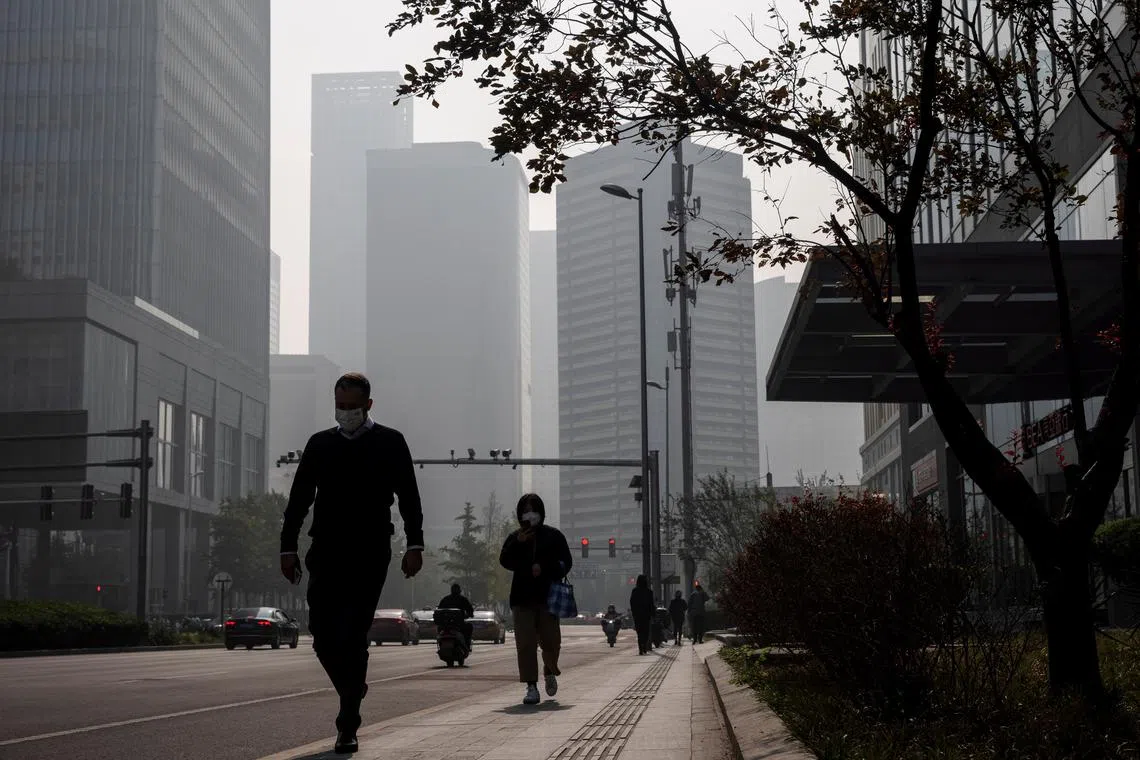 People walk in the Central Business District (CBD) on a hazy morning in Beijing, China, October 25, 2021.   REUTERS/Thomas Peter/file photo