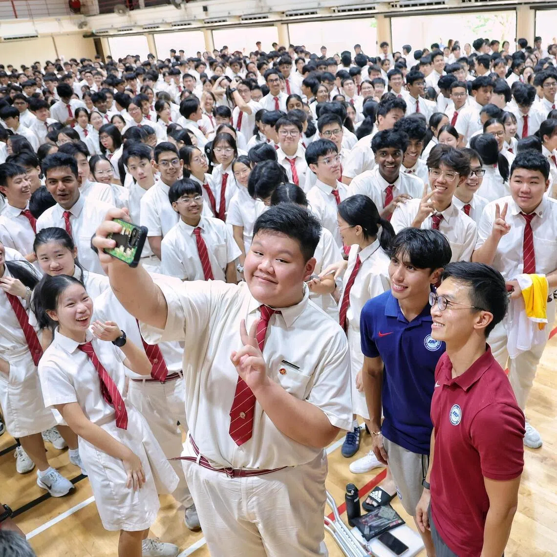 Lions head coach Gavin Lee (maroon top) and winger Glenn Kweh (dark blue top) taking a wefie with student Clarence Kuan during an engagement session at Victoria Junior College on Feb 23, 2026.