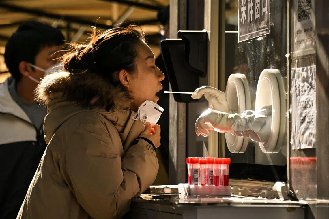 A health worker takes a swab sample from a woman to be tested for the Covid-19 at a swab collection site in Beijing, on Dec 11, 2022. 