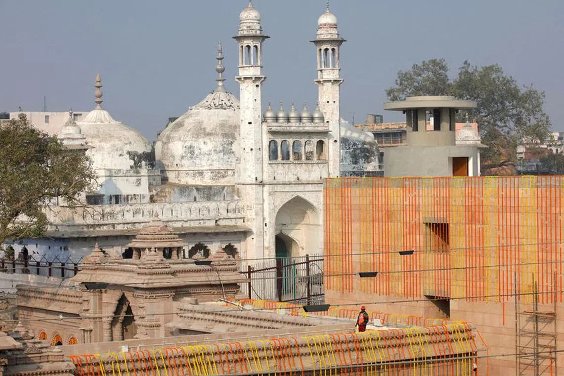 FILE PHOTO: A worker stands on a temple rooftop adjacent to the Gyanvapi Mosque  in the northern city of Varanasi, India, December 12, 2021. REUTERS/Pawan Kumar/File Photo