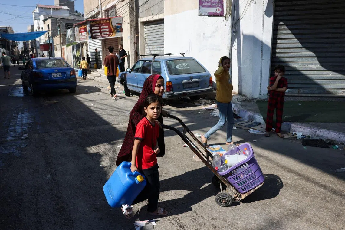 Palestinians carry empty bottles and containers as they look to refill on water at the Rafah refugee camp, in the south of the Gaza Strip.