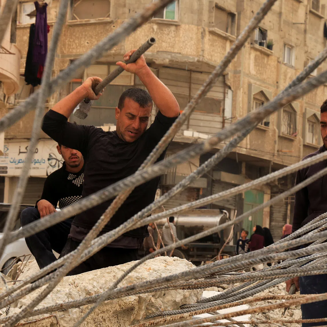 Palestinian workers break concrete to extract steel bars from destroyed homes, relying only on simple hand tools amid a severe shortage of construction materials caused by long-standing restrictions on the entry of cement and iron, in Khan Younis in the southern Gaza Strip, December 9, 2025. REUTERS/Haseeb Alwazeer