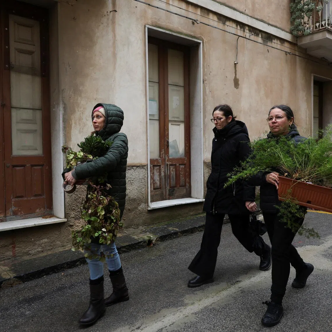 Benedetta Ragusa (L) and her friends remove flowerpots from her pizzeria as residents scramble to remove belongings and mementos from homes in high-risk areas following a landslide in Niscemi, Sicily, Italy, January 31, 2026. REUTERS/Fatos Bytyci
