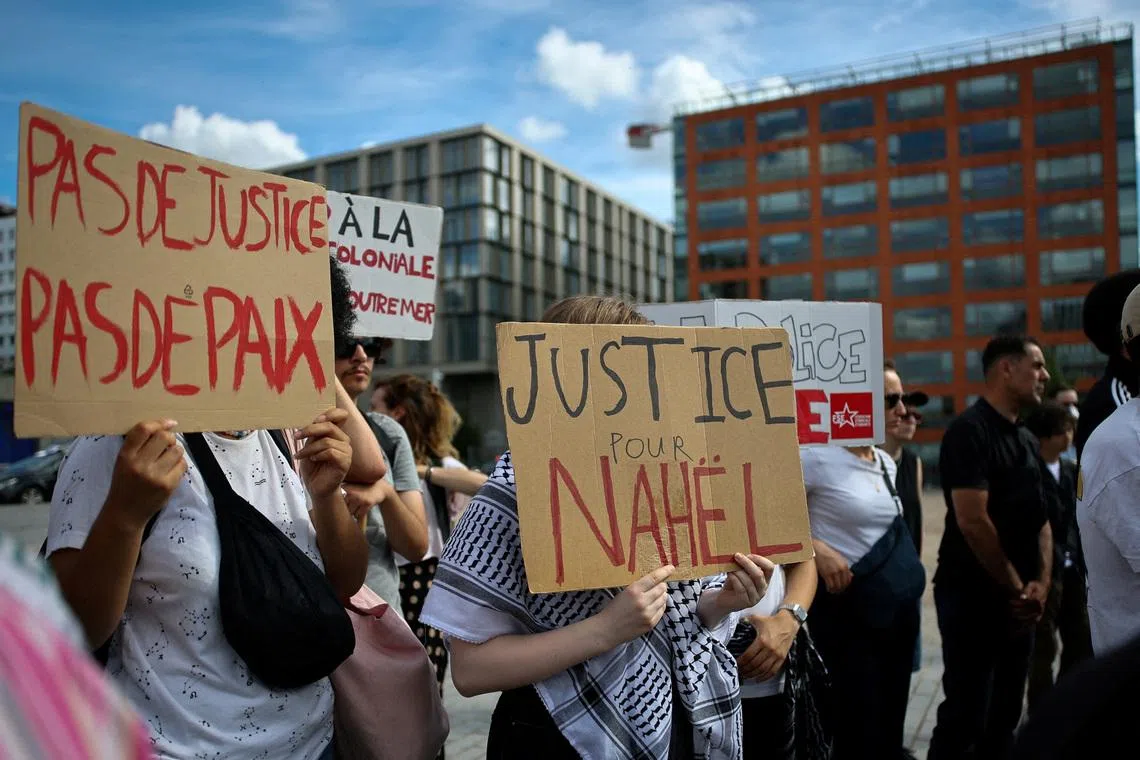 FILE PHOTO: People hold placards during a demonstration to demand justice two years after the death of Nahel, a 17-year-old teenager killed by a French police officer during a traffic stop, in Nanterre, near Paris, France, June 27, 2025. REUTERS/Gonzalo Fuentes/File Photo