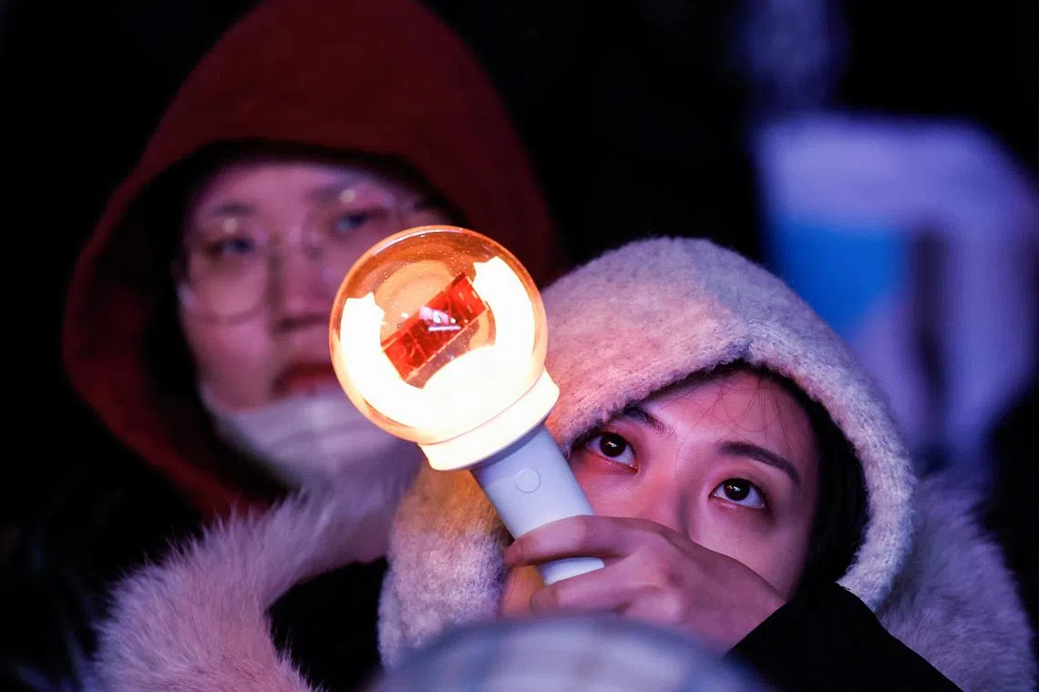A woman holds a torch light after South Korean President Yoon Suk Yeol, who declared martial law which was reversed hours later, survived an impeachment motion, at a rally in front of the National Assembly in Seoul, South Korea, December 7, 2024. REUTERS/Kim Kyung-Hoon