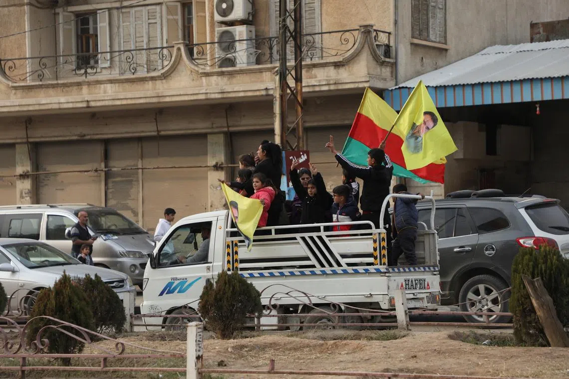 People waving flags ride in the back of a truck, after rebels seized the capital and ousted President Bashar al-Assad, in Qamishli, Syria December 8, 2024. REUTERS/Orhan Qereman