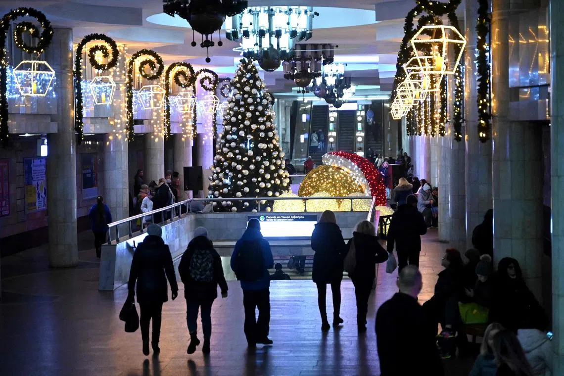 Passengers walk along a platform decorated with a Christmas tree at a subway station in Kharkiv on December 22, 2023, amid the Russian invasion of Ukraine. (Photo by SERGEY BOBOK / AFP)