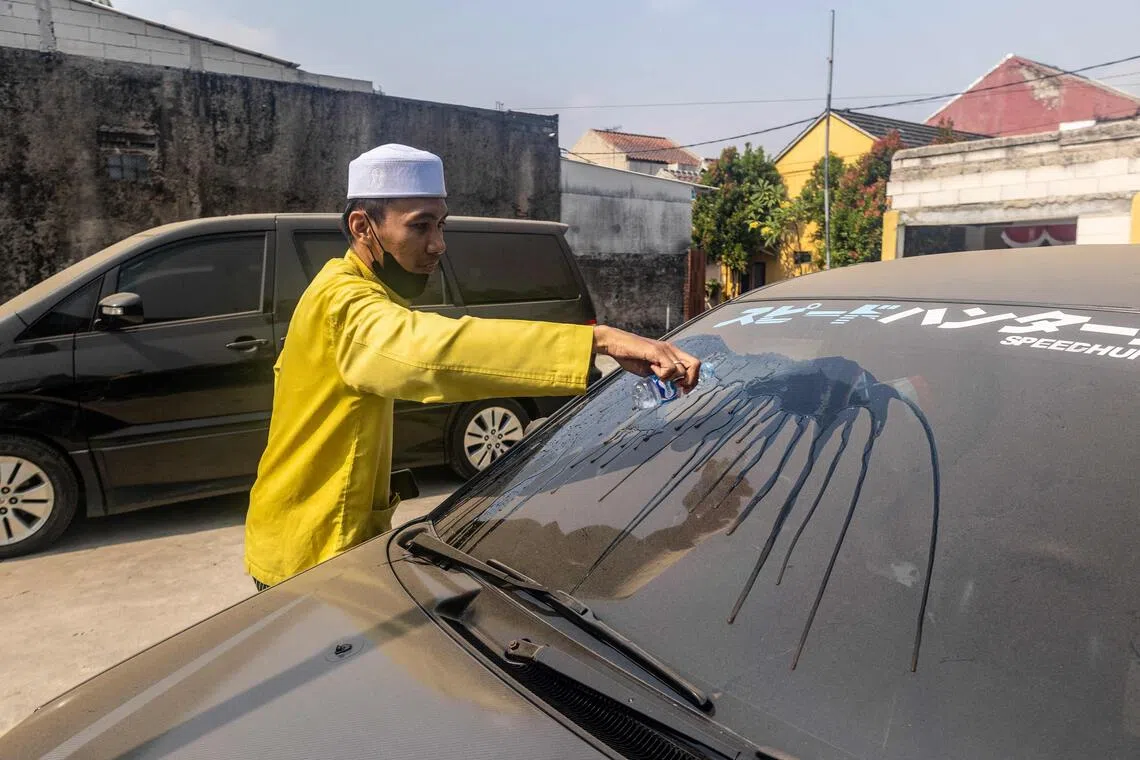 A man clearing volcanic ash from his car windscreen in Bogor, West Java, on Sept 6, following the eruption of Anak Krakatau.