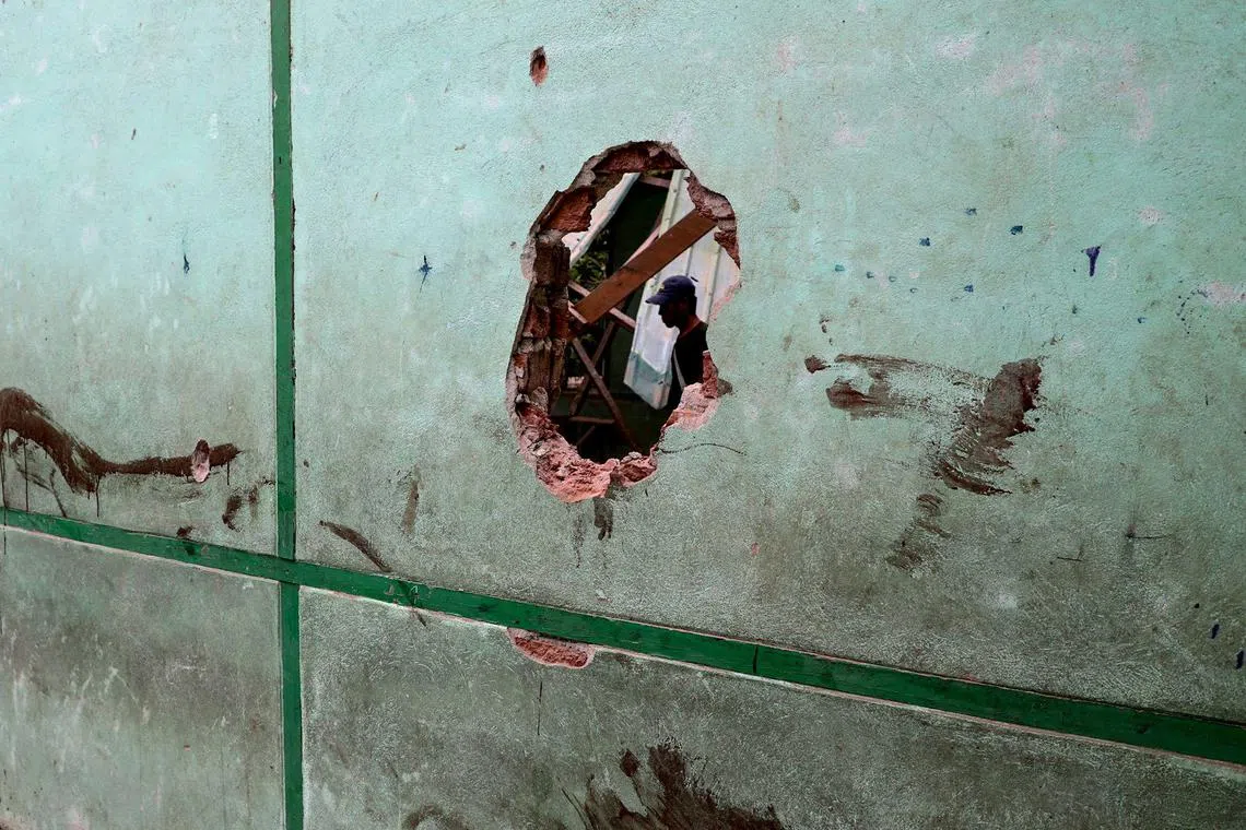 A man is pictured through a damaged wall of a school building following a bombardment carried out by Myanmar's military at the Ohe Htein Twin village in Tabayin township, Sagaing region, on May 12.