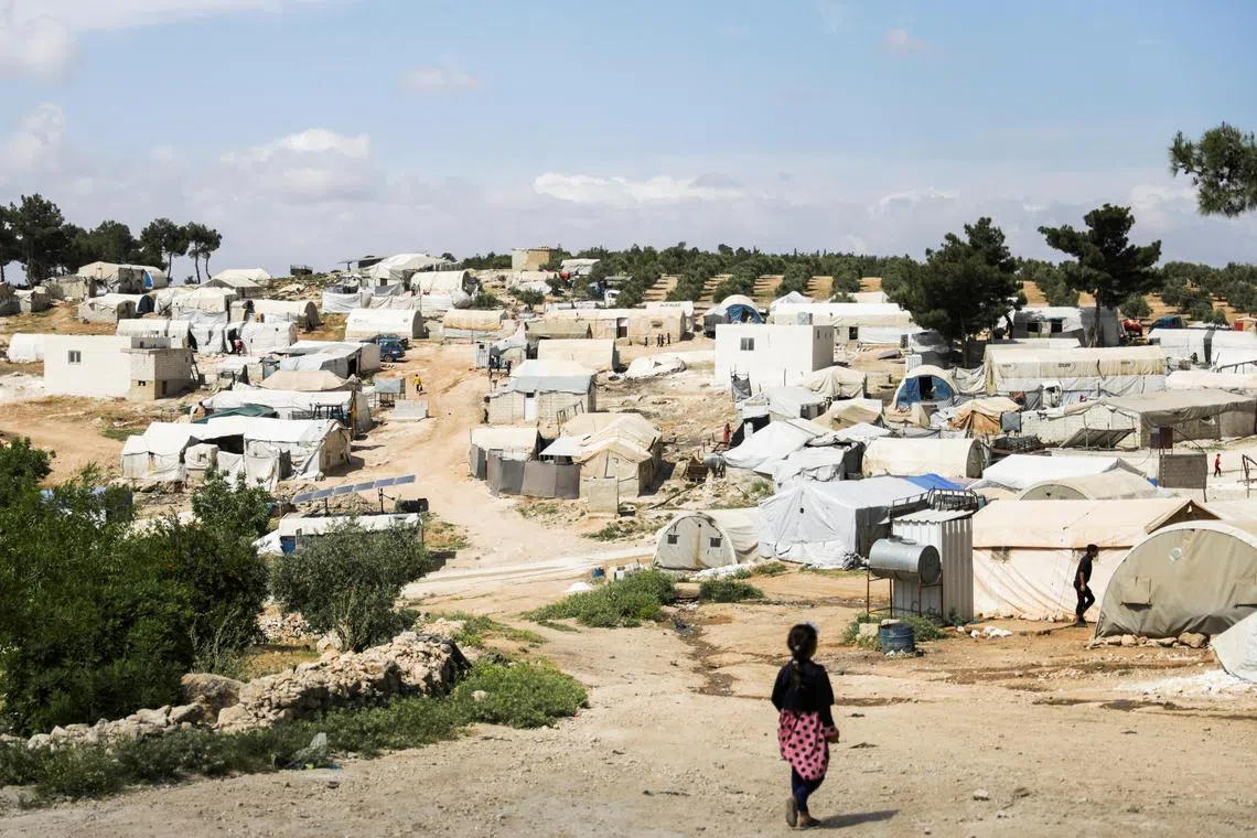 A girl walks near tents at camp in Syria for internally displaced people, in May 2023.