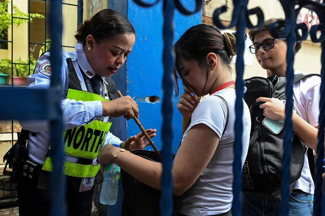 A security guard checks a student’s bag as she enters Batasan Hills National High School, a day after at least three students were killed and seven others injured when two students fire at a school in the city of Tacloban southeast ​of Manila.