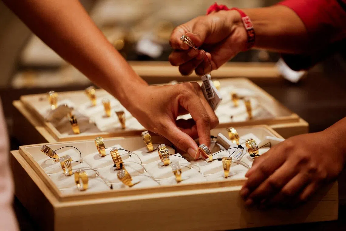 FILE PHOTO: A salesperson shows a gold ring to customers at a jewellery showroom in Ahmedabad, India, October 8, 2025. REUTERS/Amit Dave/File Photo