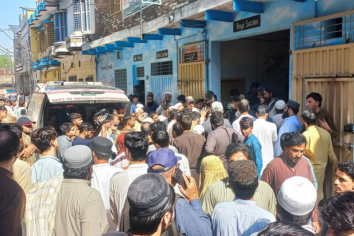 Residents and rescue workers gather near an ambulance after a school roof collapse in Peshawar, Pakistan.