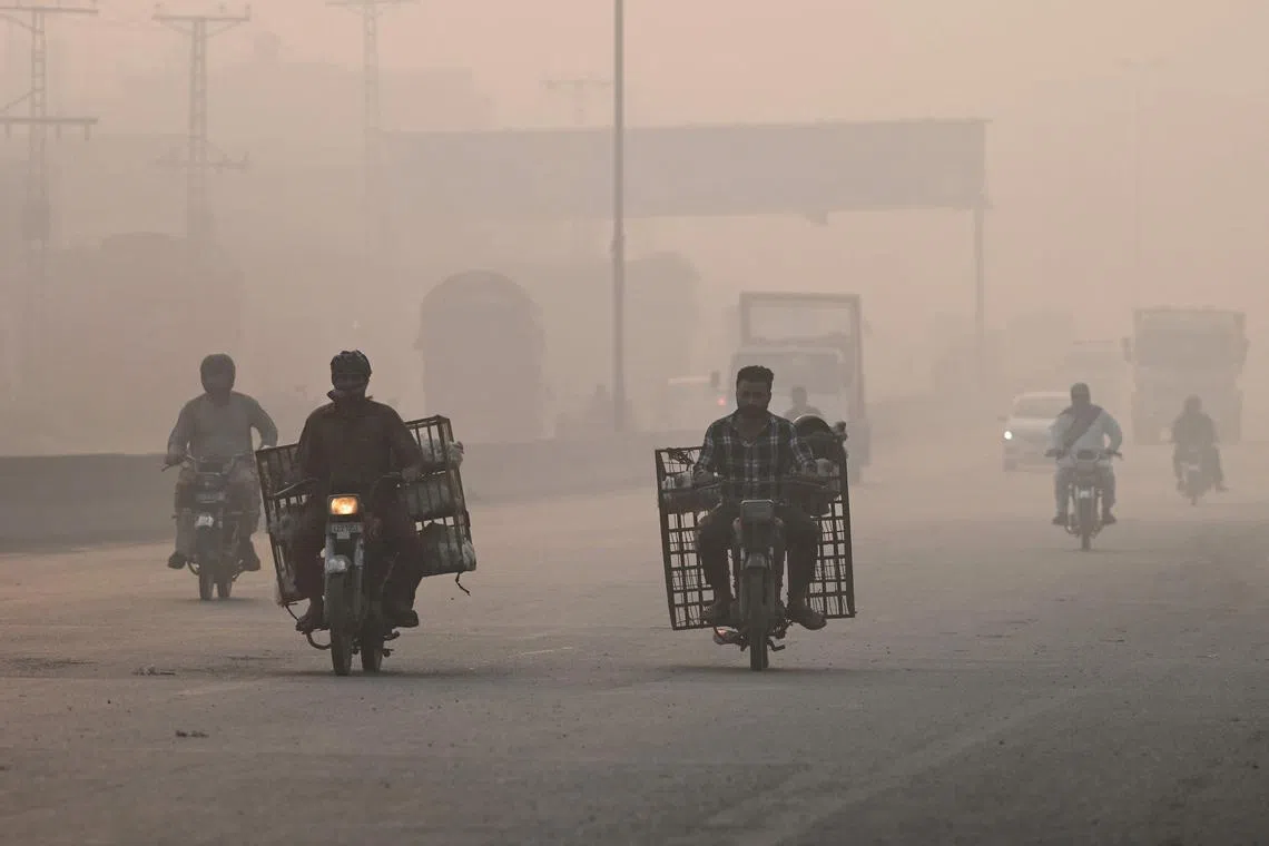 Commuters make their way amid smog in Lahore on Nov 2. 