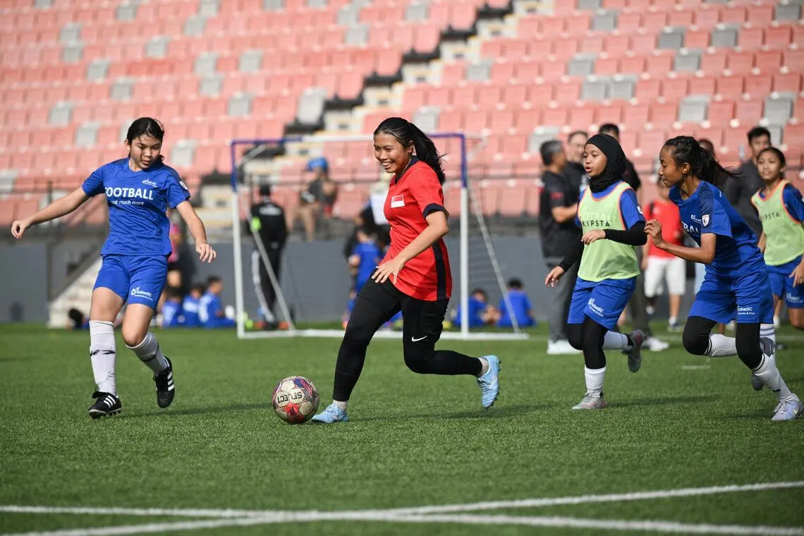 National women's footballer Irsalina Irwan (in red) playing against ActiveSG Football Academy players in an exhibition match at the AFA Football Fiesta on May 24.