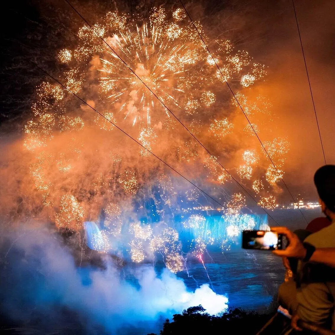 Visitors watching fireworks over an illuminated Niagara Falls, as part of the 11-state landmarks light-up for Game 3 of the NBA Finals between the New York Knicks and San Antonio Spurs, in Niagara Falls, New York, US, June 8.