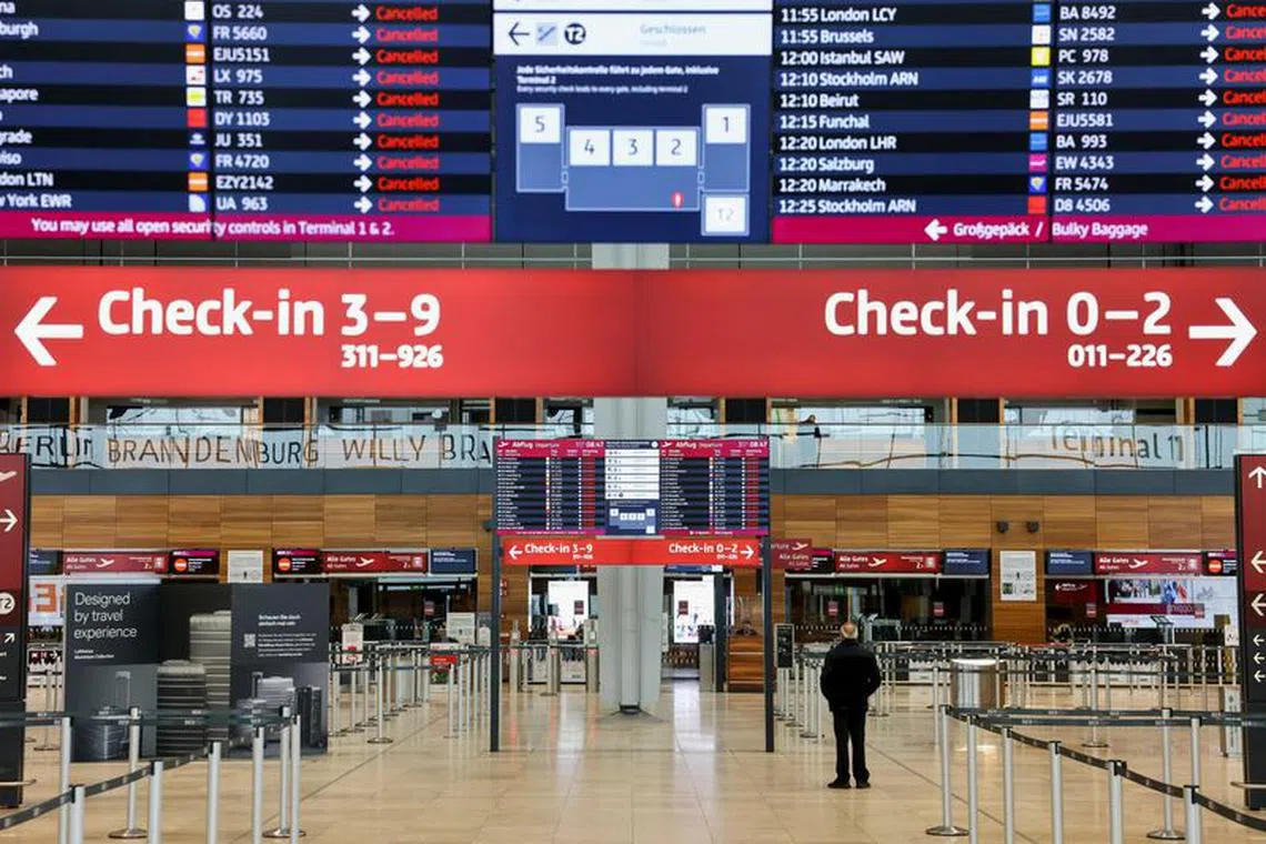 FILE PHOTO: A man stands near a departures board, as airport workers protest at BER airport during a strike called by German trade union Verdi, in Berlin, Germany, March 13, 2023. REUTERS/Christian Mang/File Photo