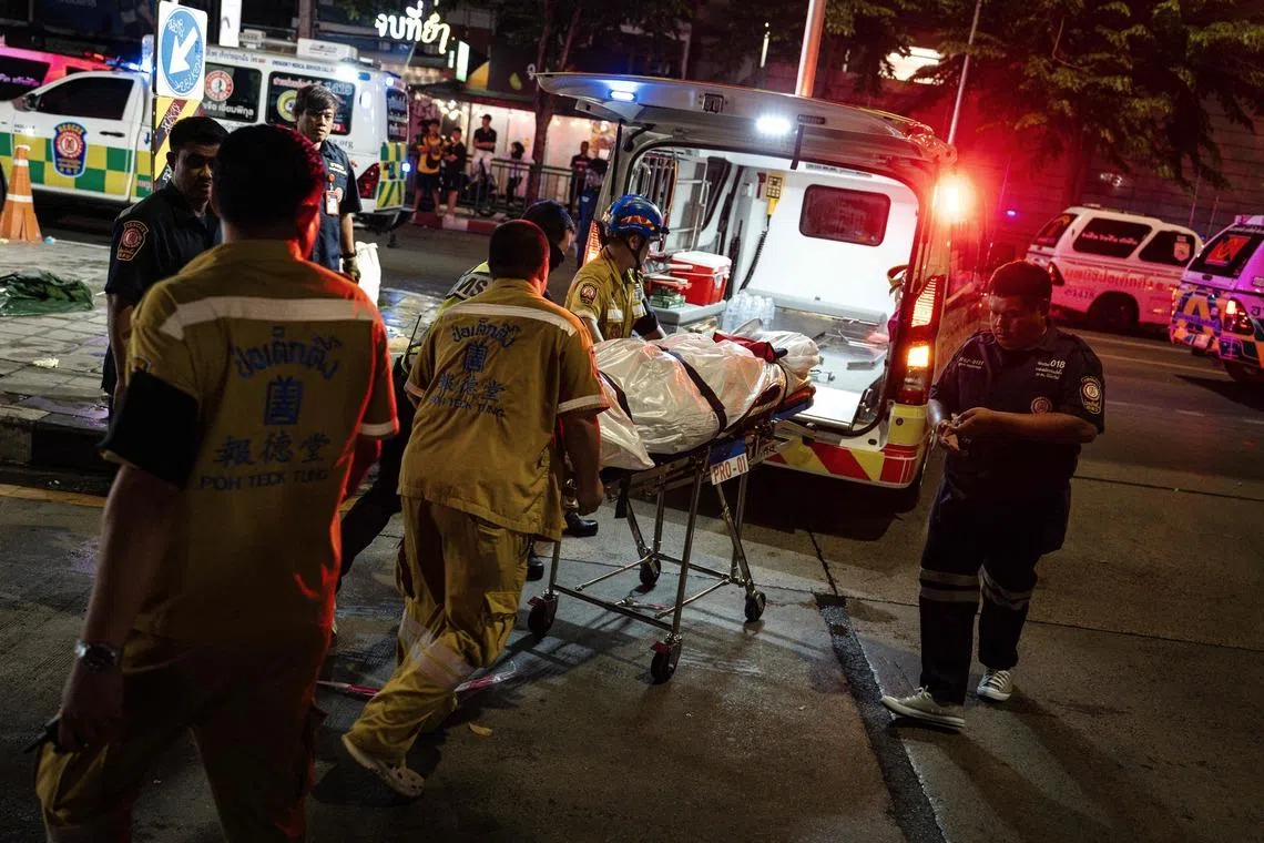 Emergency workers moving a victim’s body to an ambulance after a fire broke out at 11.57pm on July 12 at Bangkok’s Rong Beer Na Lat Phrao bar-restaurant.