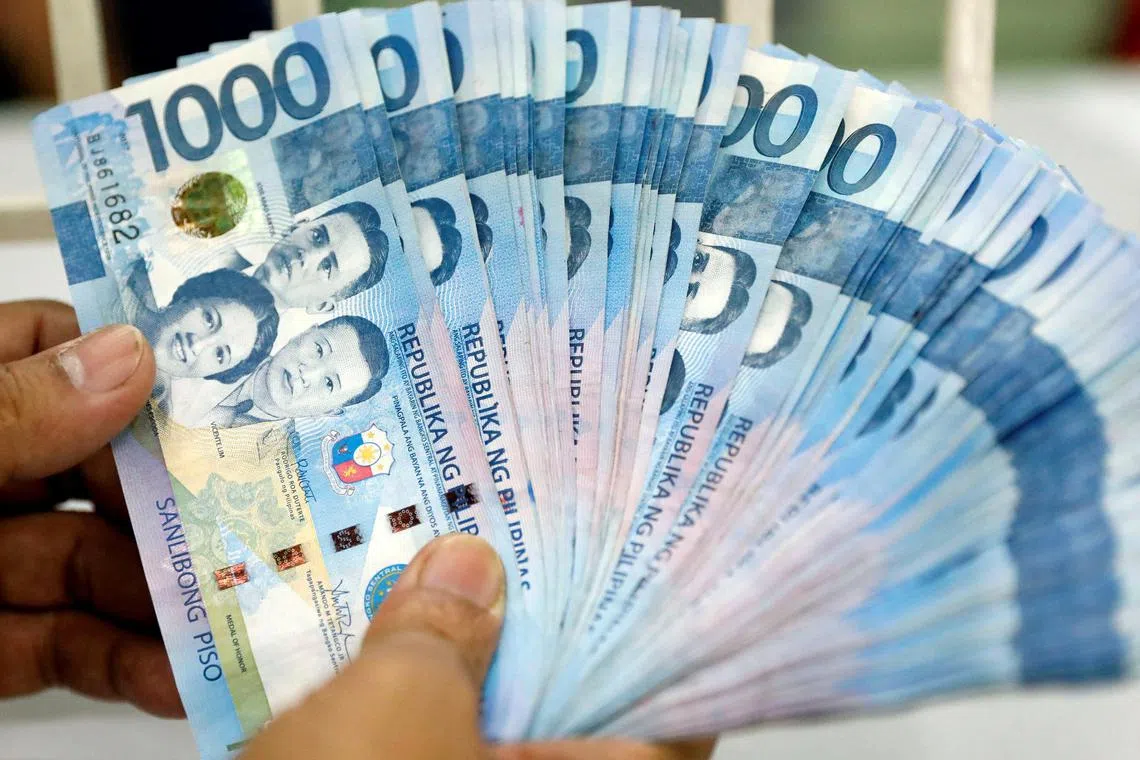 FILE PHOTO: A worker shows Philippine peso bills inside a money changer in metro Manila, Philippines August 14, 2017. REUTERS/Dondi Tawatao/File Photo