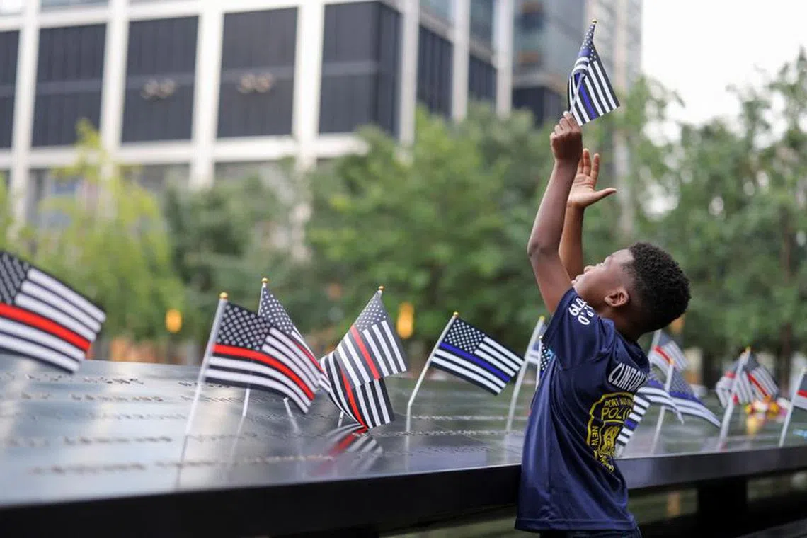 A person holds a flag, on the day of the 22nd anniversary of the September 11, 2001 attacks on the World Trade Center at the National September 11 Memorial & Museum, in New York City, U.S., September 11, 2023. REUTERS/Andrew Kelly