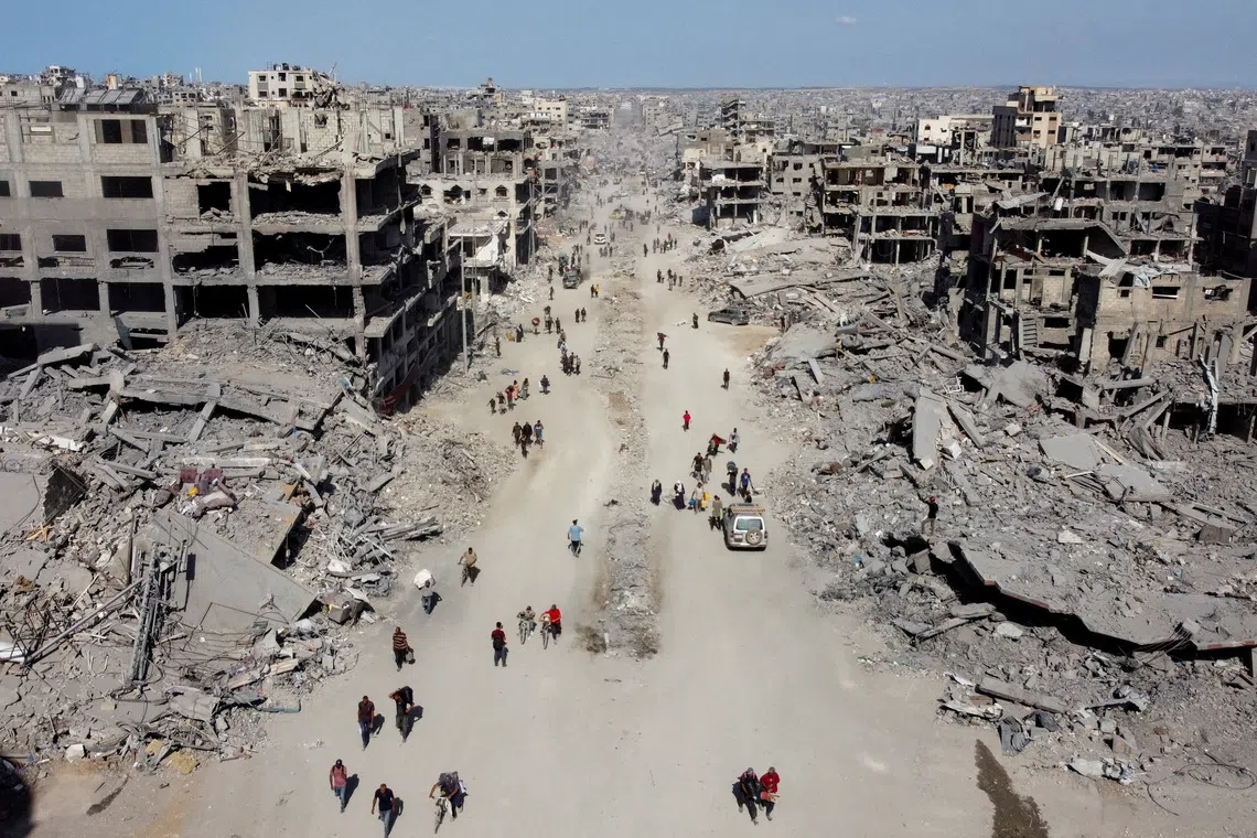A drone view shows Palestinians walking past the rubble, following Israeli forces' withdrawal from the area, amid a ceasefire between Israel and Hamas in Gaza, in Gaza City, October 11, 2025. REUTERS/Dawoud Abu Alkas/File Photo