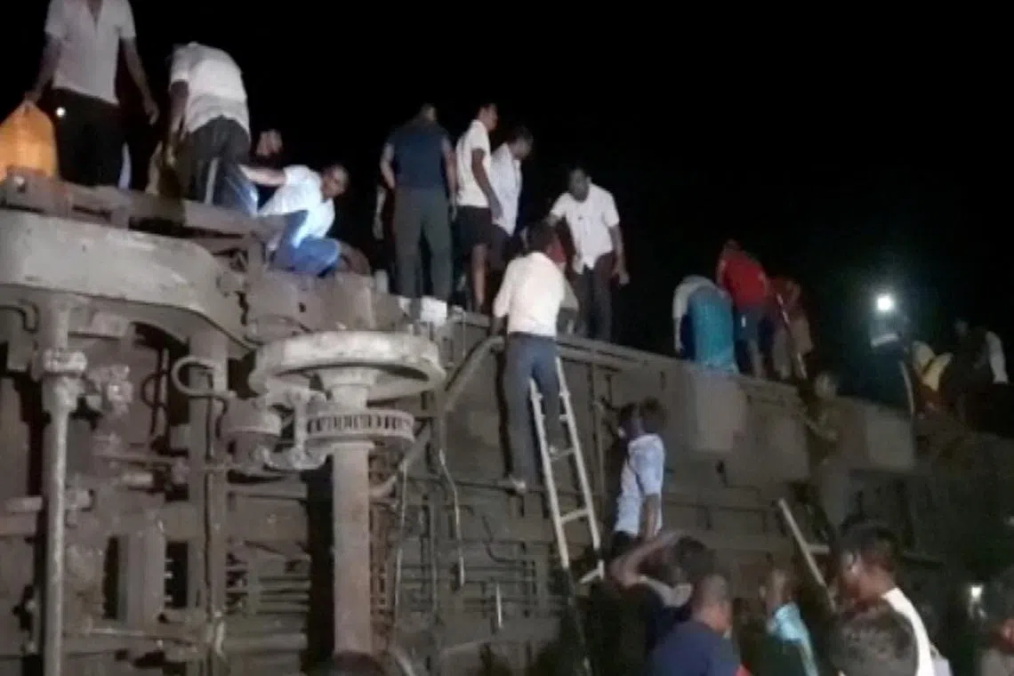 People try to escape from toppled compartments, following the deadly collision of two trains.