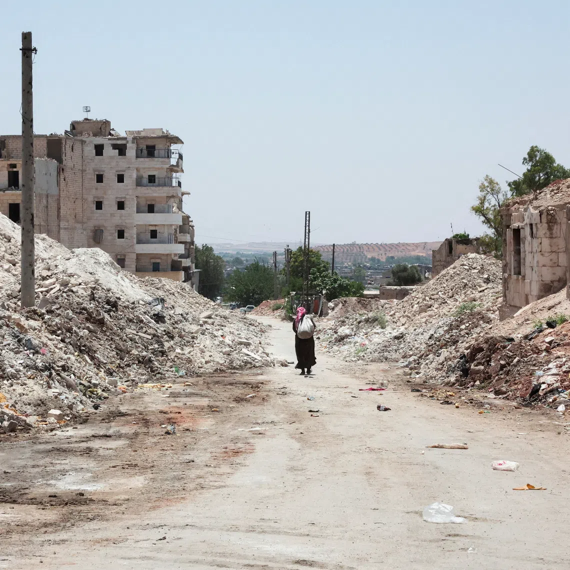 FILE PHOTO: A man walks through the destruction in the city of Aleppo, Syria, June 23, 2025. REUTERS/Mahmoud Hassano/File Photo