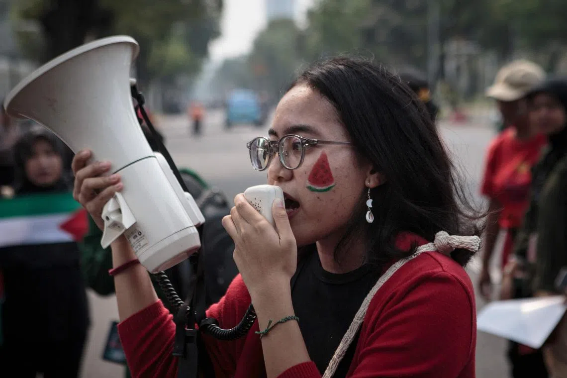 A woman with watermelon face paint shouts slogans during a protest in solidarity with the Palestinian people, in front of the US embassy in Jakarta.