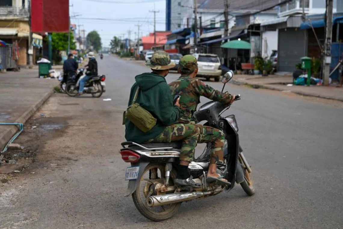 Soldiers ride a motorcycle along a street in Oddar Meanchey province on December 10, 2025 following clashes along the Cambodia-Thailand border. Fighting between Thailand and Cambodia spread to more parts of their contested border on Tuesday, forcing a mass exodus of civilians as the renewed hostilities derailed a US-brokered truce.
