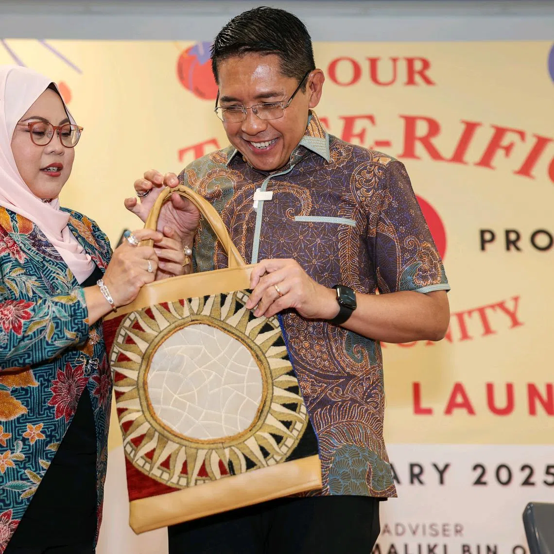 Second Minister for Education and Foreign Affairs, Dr Mohamad Maliki Osman, and his wife Sadiah Shahal, unveiling the tote bag they designed during the launch of the Tote-rific Community initiative.
