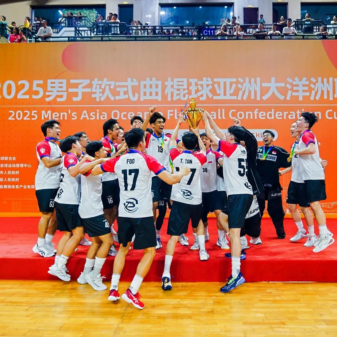 The Singapore men's floorball team lifting their trophy after winning the Asia Oceania Floorball Confederation Cup in China.