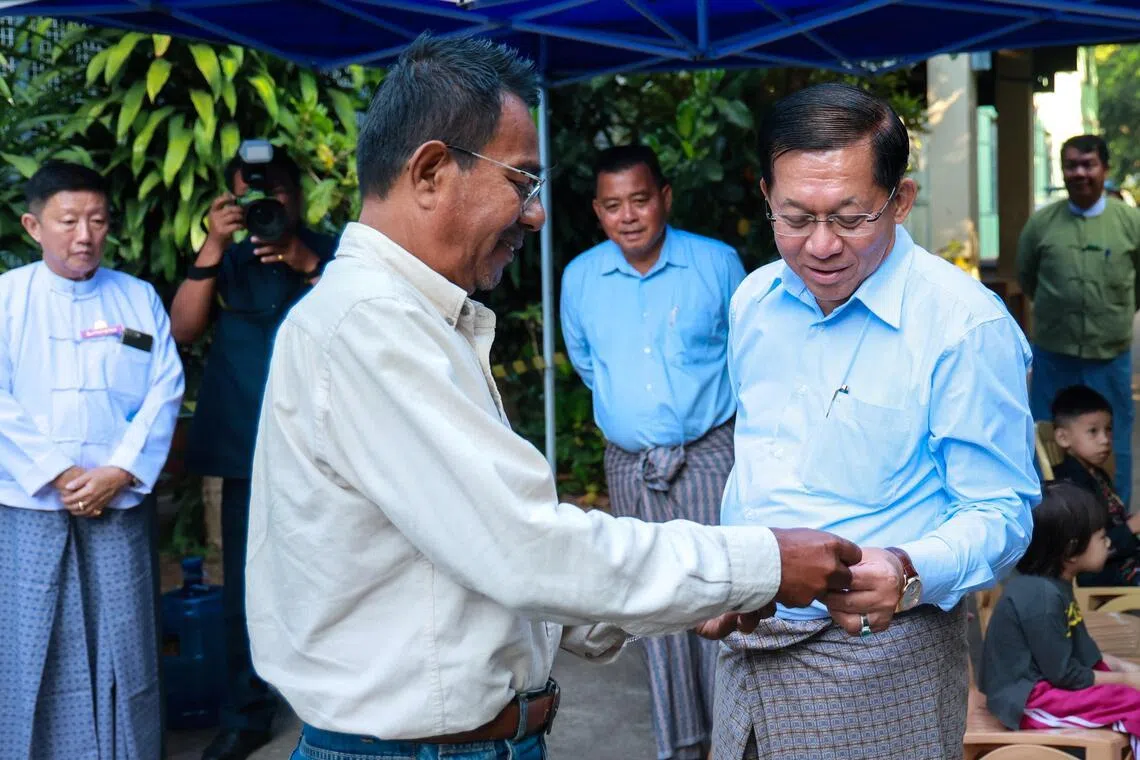 Myanmar’s junta chief Min Aung Hlaing (right) speaks to a man outside a polling station during the second phase of a general election in Yangon, Myanmar, on Jan 11.