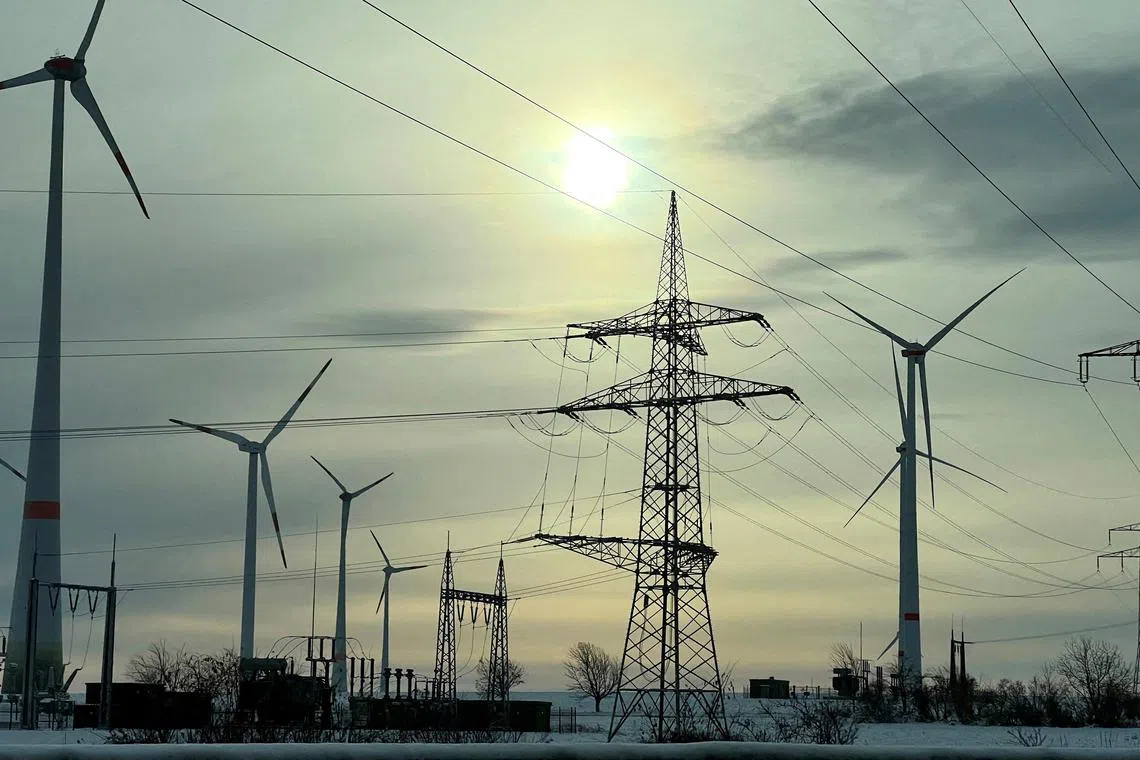 FILE PHOTO: Power-generating windmill turbines and power lines are seen in a snow-covered wind park in Krauschwitz, Germany, December 4, 2023. REUTERS/Fabrizio Bensch/File Photo